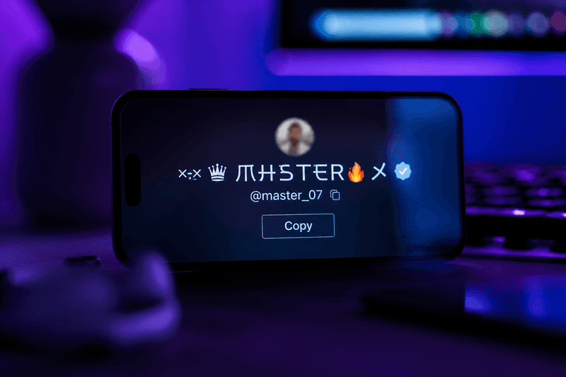 Person customizing a stylish username on their phone at a desk with natural window light